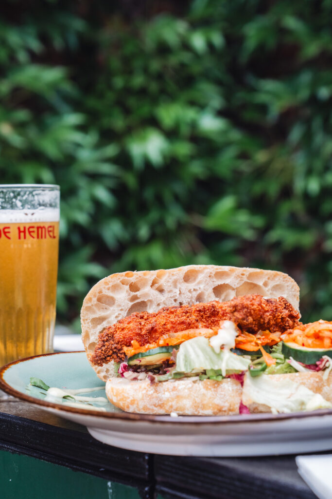 Broodje crispy chicken met een glas bier bij De Hemel