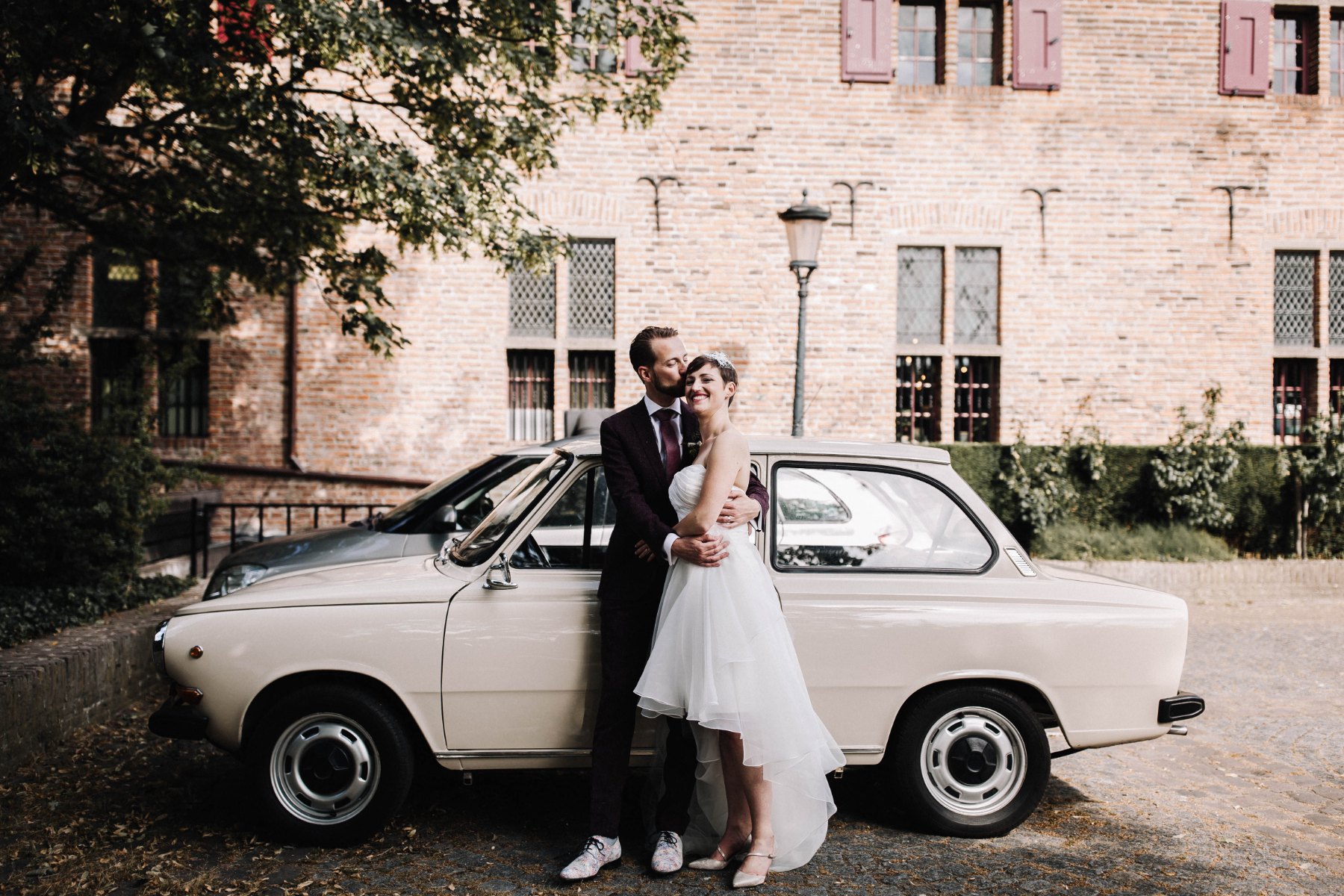 Los novios junto a un coche clásico delante de la Commanderie van Sint Jan en Nimega