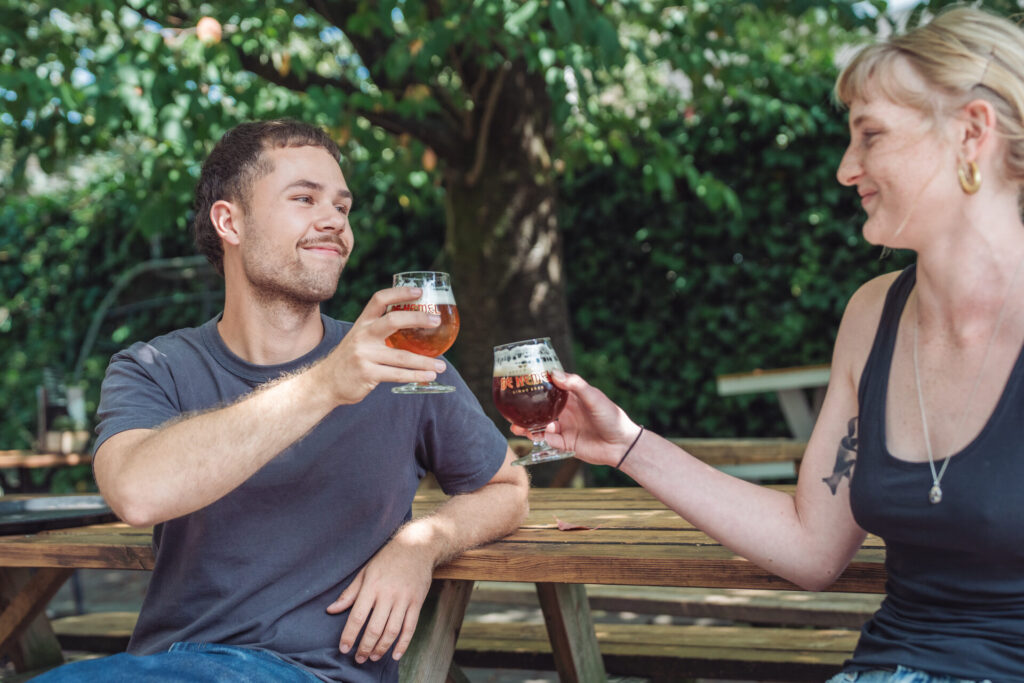 Gasten proosten met huisgebrouwen bier op het terras van De Hemel