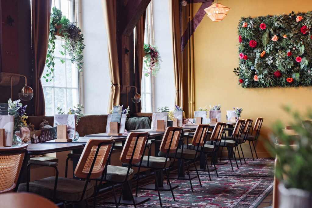 De restaurantzaal van De Hemel met hoge ramen en gordijnen