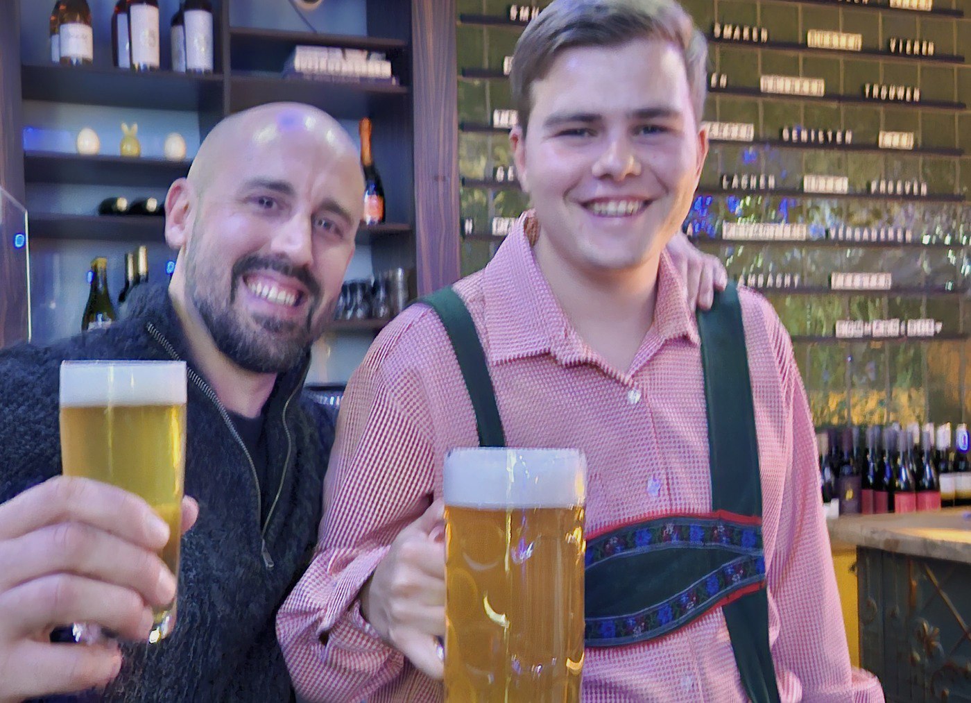 Twee gasten proosten met een pul bier aan de bar